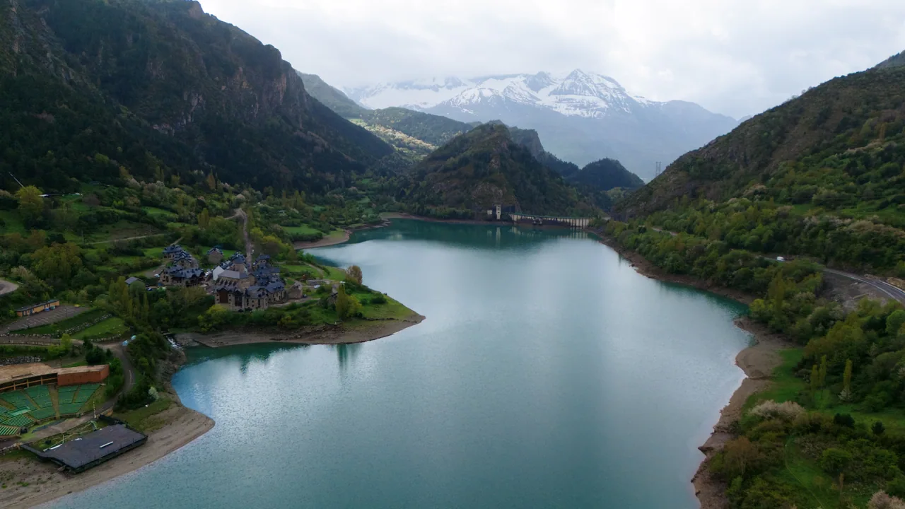 Embalse entre montañas con picos nevados al fondo